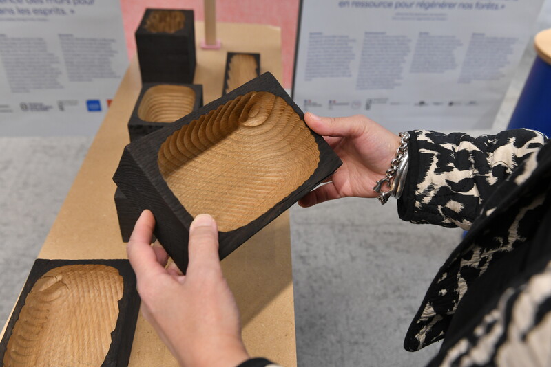 Une personne qui tient en main une boite en bois coloré en noir que l'extérieur